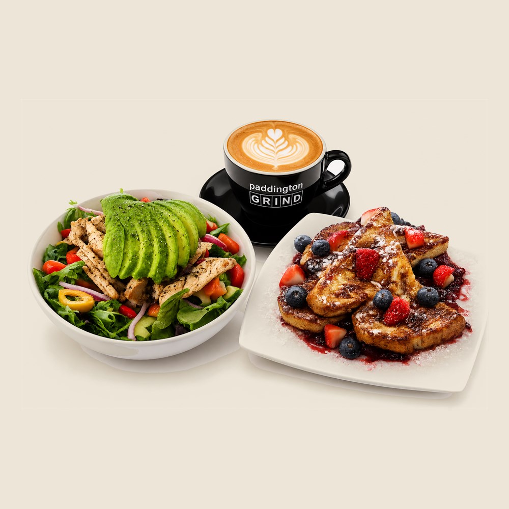 A grilled chicken and avocado salad, a latte in a black Paddington Grind cup, and berry french toast.
