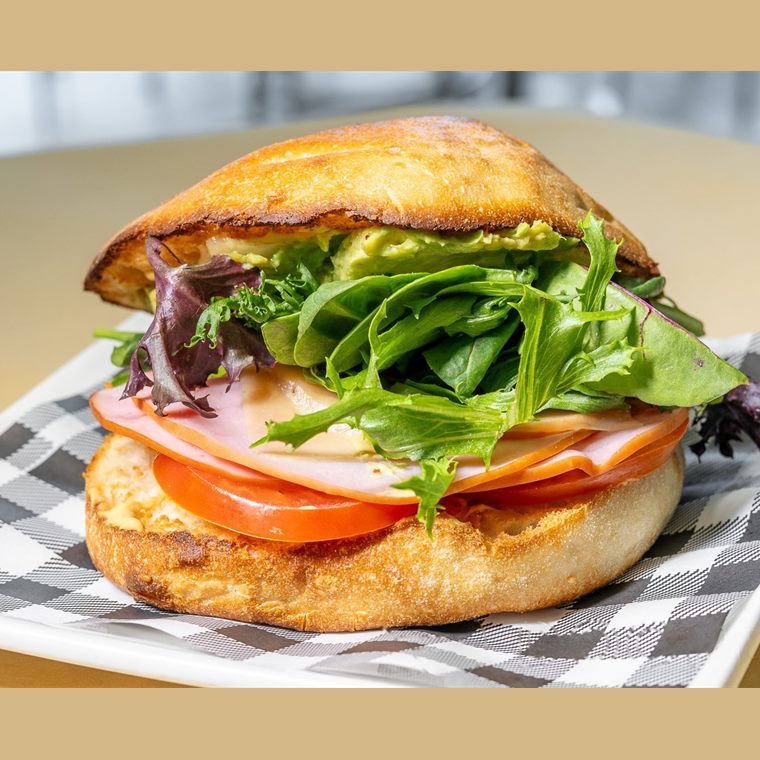 A BLAT roll stacked with bacon, lettuce, avocado and thick slices of tomato.