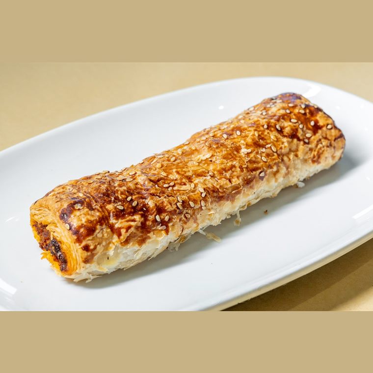 A long chorizo roll baked with cheese on top, on a white platter.