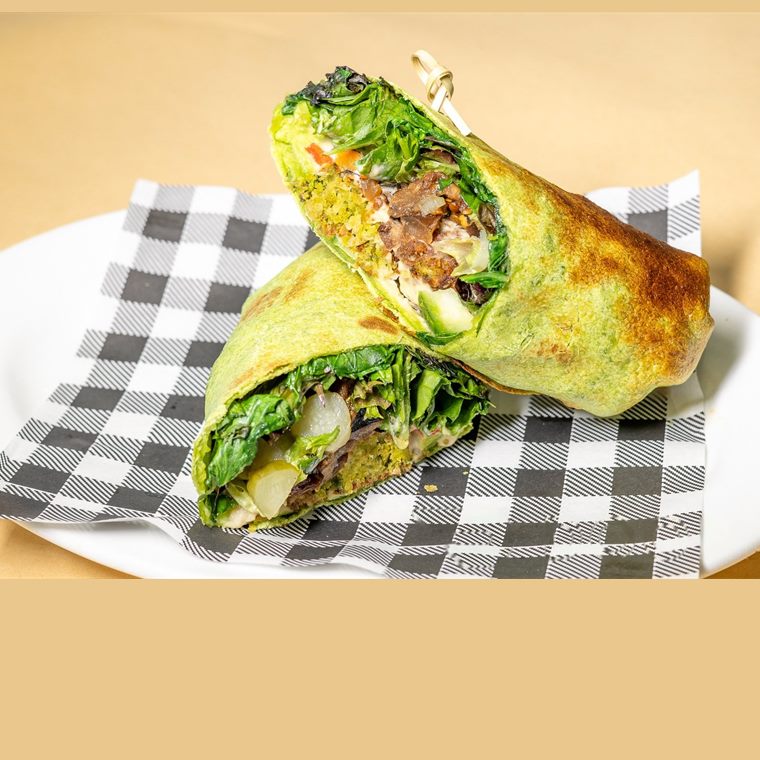 A falafel wrap with hummus, cucumber, pickles, lettuce and grilled capsicum.