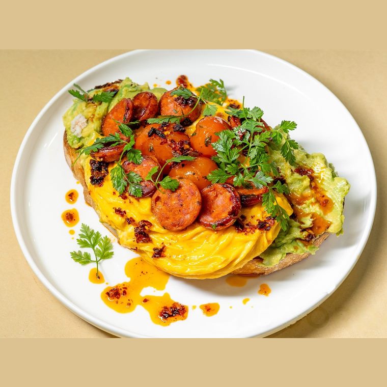 A folded scramble topped with roast cherry tomatoes, avocado, coriander and chilli oil.