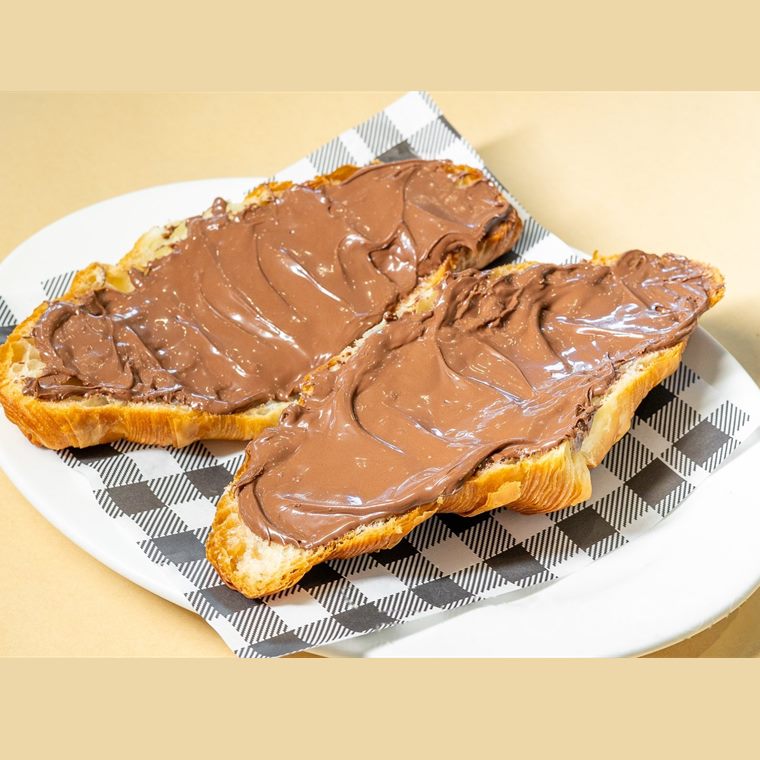 A croissant split open and spread thickly with Nutella.