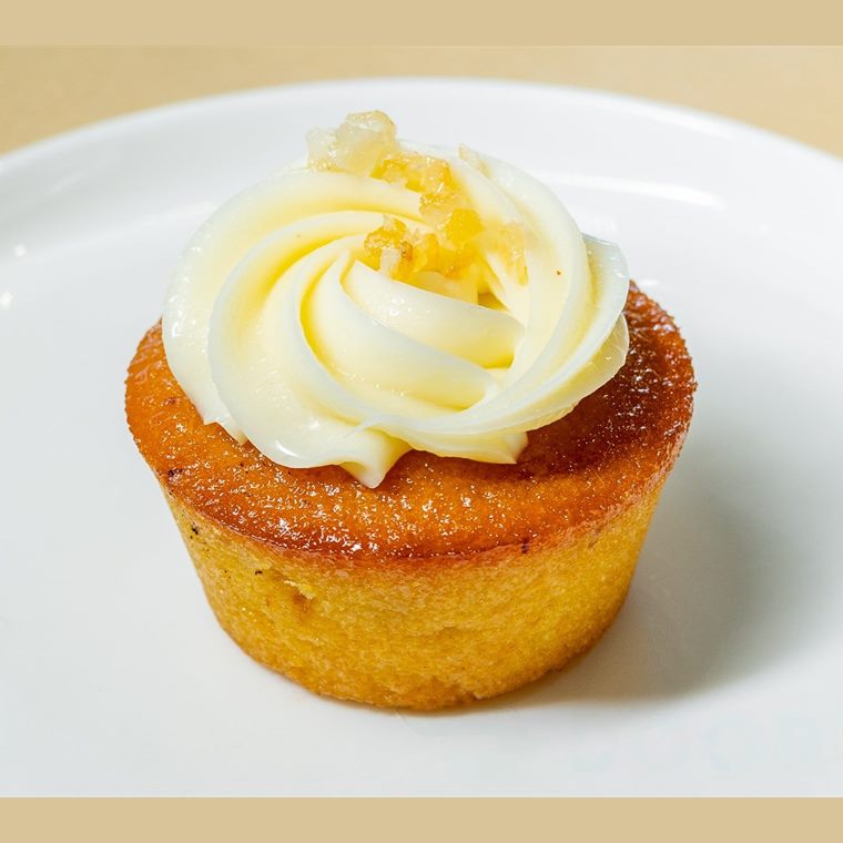 A small round orange cake topped with a swirl of whipped cream.