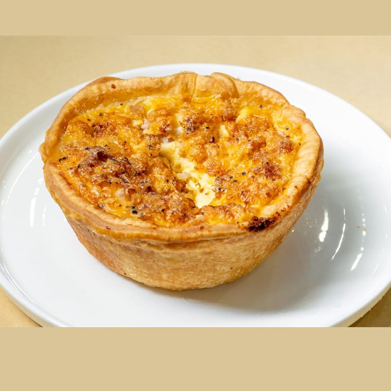 An individual quiche with a golden pastry case.
